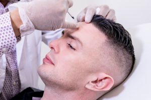 Caucasian man undergoing beauty spa botulinum neurotoxin Botox treatment for anti-aging, to smooth wrinkles as a cometic solution. Injecting forehead to relax muscles with a non-invasive botox.